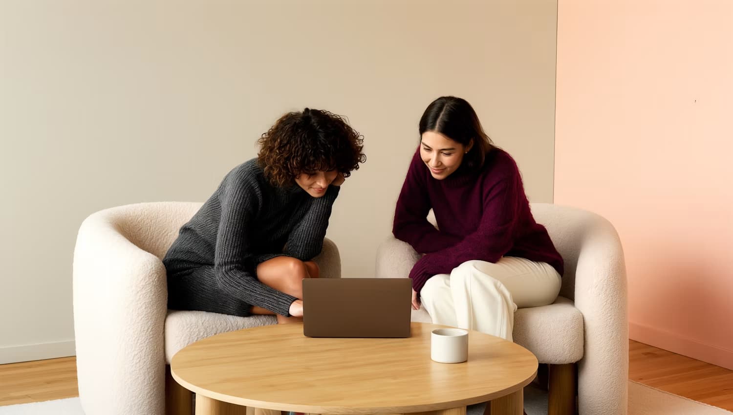 Deux collègues échangent autour d’un ordinateur portable, installées dans des fauteuils