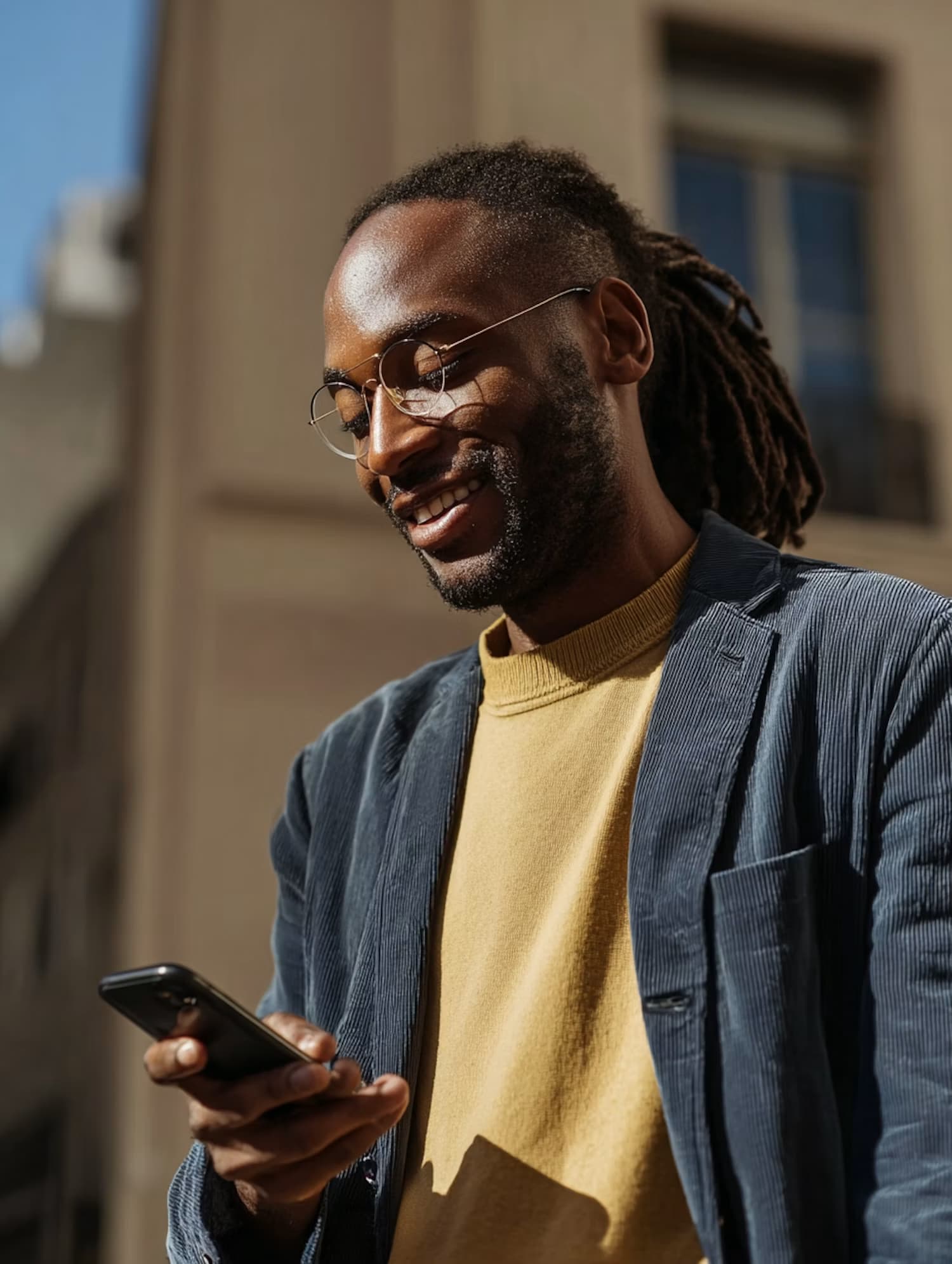 Un homme consulte son téléphone en souriant, dans la rue