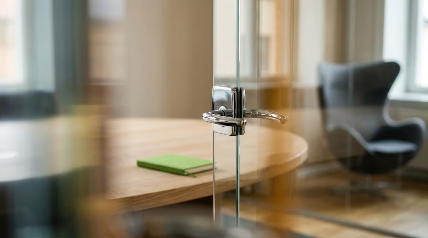 La poignée d’une porte vitrée ouvrant sur une salle de réunion