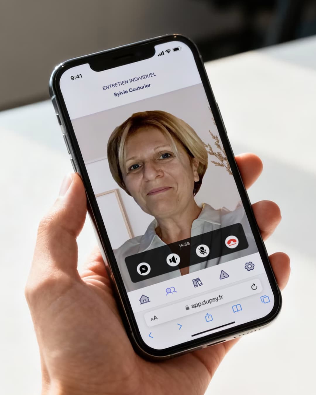 Un smartphone tenu à deux mains affiche un entretien individuel en visioconférence avec une psychologue