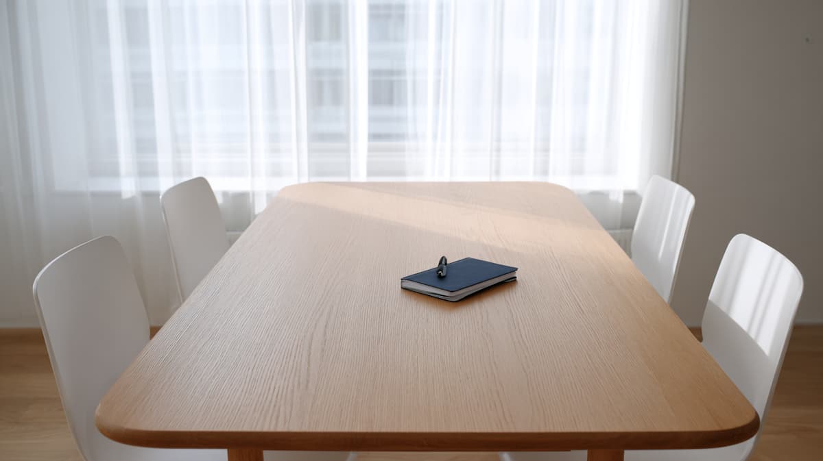 Une table de bureau vide, carnet et stylo posés dessus